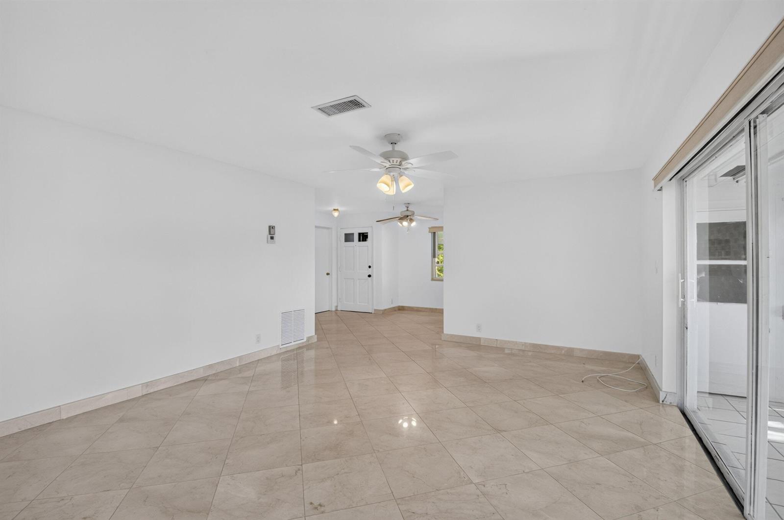 An empty room with white walls, beige tile flooring, and two ceiling fans — 300 NW 42nd Street, Boca Raton FL 33431, BOCA RATON, FL