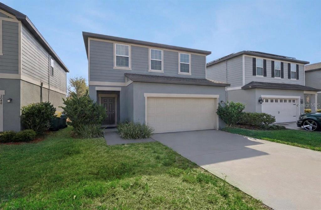 A two-story house with gray siding, a tan garage door, and a concrete driveway — 2044 CADES COVE WAY, DELAND, FL