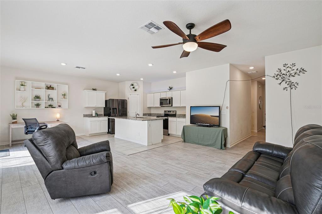 An open-concept living room and kitchen featuring light tile flooring and a ceiling fan — 2044 CADES COVE WAY, DELAND, FL