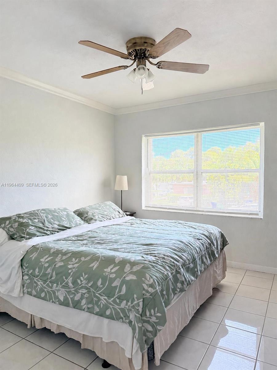 A bedroom features a bed with a green floral comforter, tile flooring, and a ceiling fan — 3411 SW 11th St # 3B, Miami FL 33135, MIAMI, FL