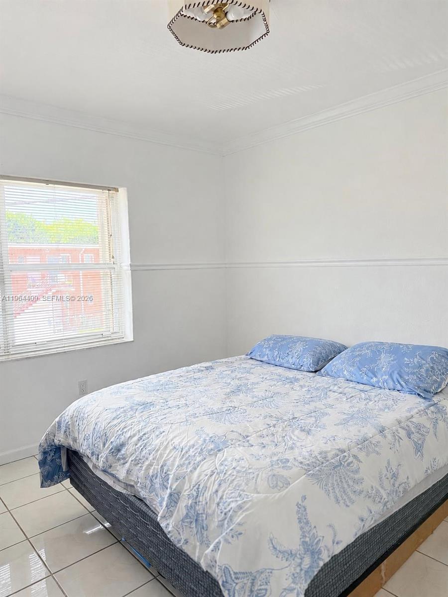 A bedroom features white walls, a tiled floor, a bed with blue patterned bedding, and a window — 3411 SW 11th St # 3B, Miami FL 33135, MIAMI, FL