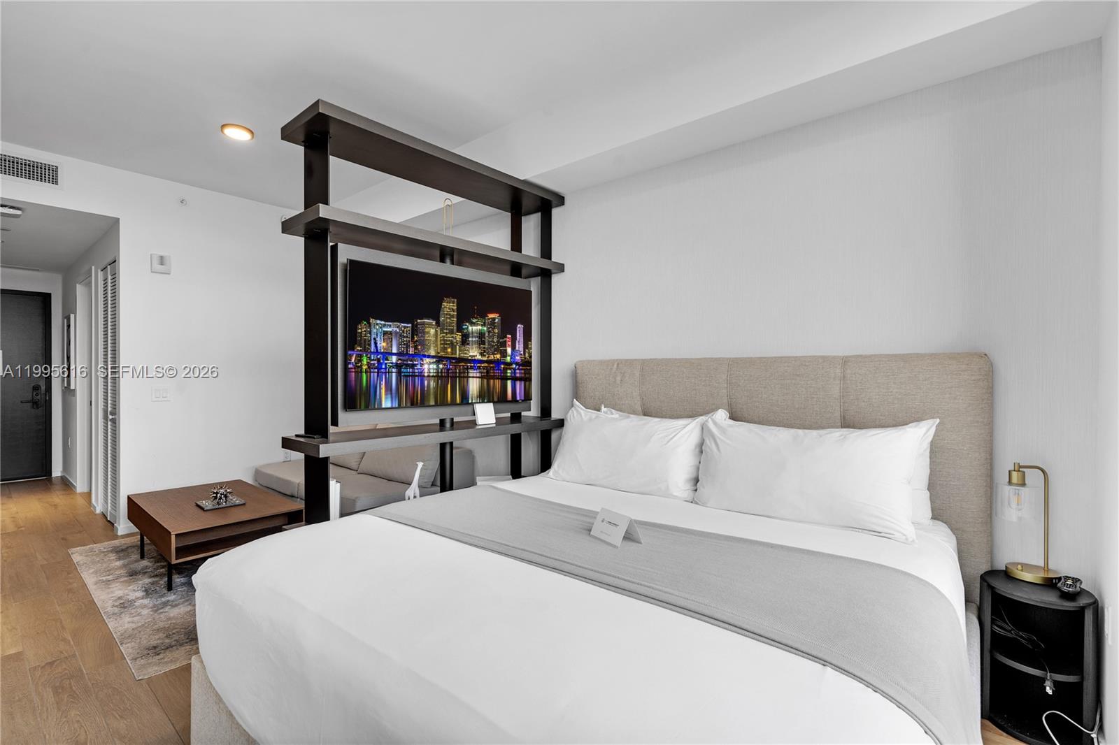 A bedroom features a bed, a television mounted on a shelving unit, and wood flooring — 398 NE 5th St # 4412, Miami FL 33132, MIAMI, FL