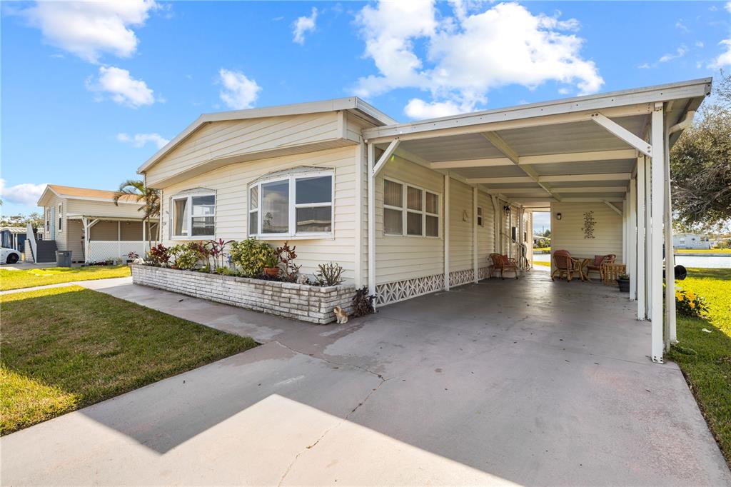A single-story manufactured home with a carport and a brick-bordered front garden — 204 51ST AVENUE E, BRADENTON, FL