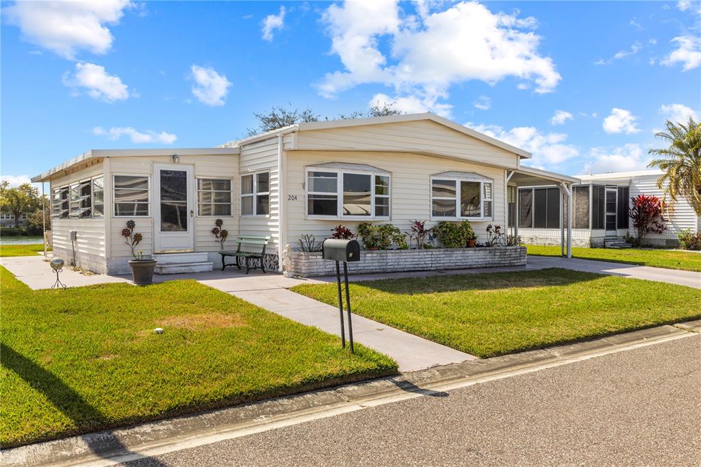 A single-story mobile home with light siding, a front lawn, and a paved driveway — 204 51ST AVENUE E, BRADENTON, FL