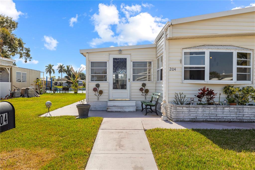 A single-story mobile home with light siding, a concrete walkway, and a small front porch — 204 51ST AVENUE E, BRADENTON, FL