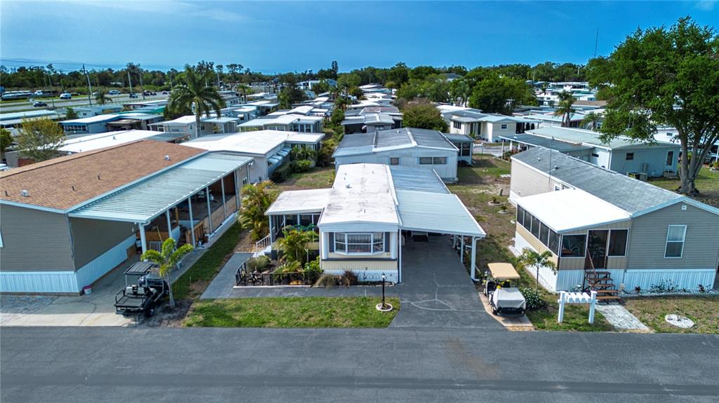 An aerial view shows several manufactured homes with carports and golf carts in a park — 420 49TH STREET E UNIT 83, PALMETTO, FL
