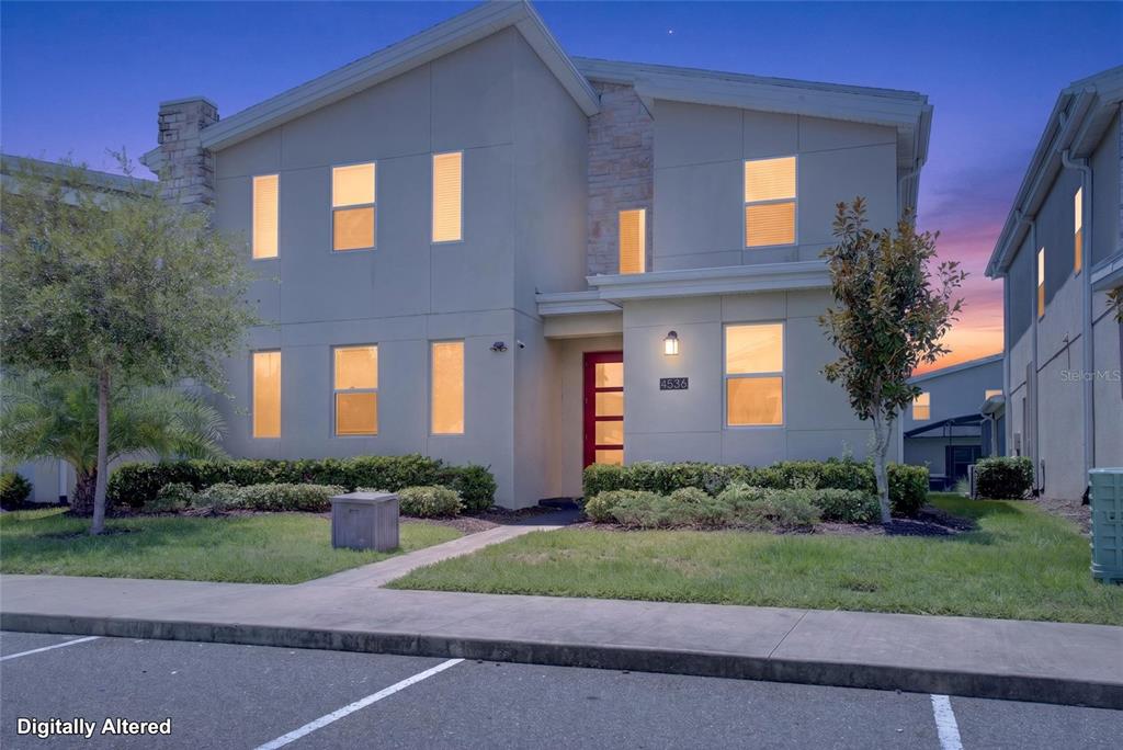A two-story house with a light-colored facade, a red front door, and a landscaped front yard — 4536 TARGET BOULEVARD, KISSIMMEE, FL
