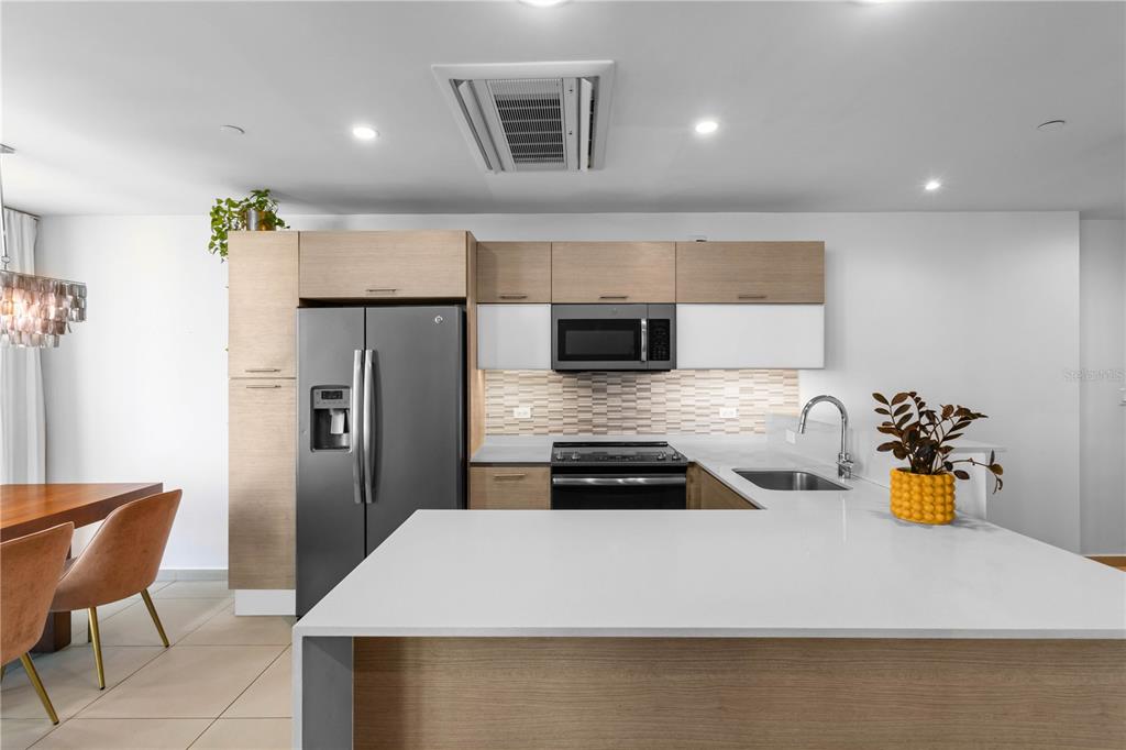 A modern kitchen features light wood cabinetry, white countertops, stainless steel appliances, and tile backsplash — 1511 PONCE DE LEON AVENUE UNIT 851, SAN JUAN, PR