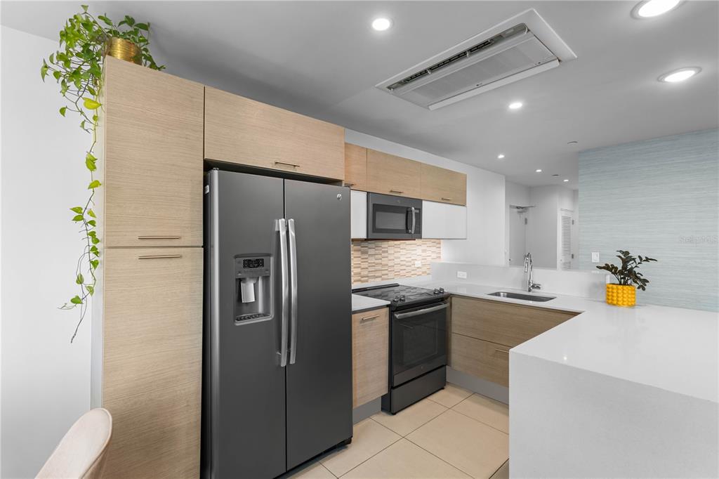 A modern kitchen features light wood cabinetry, stainless steel appliances, and a white quartz countertop — 1511 PONCE DE LEON AVENUE UNIT 851, SAN JUAN, PR