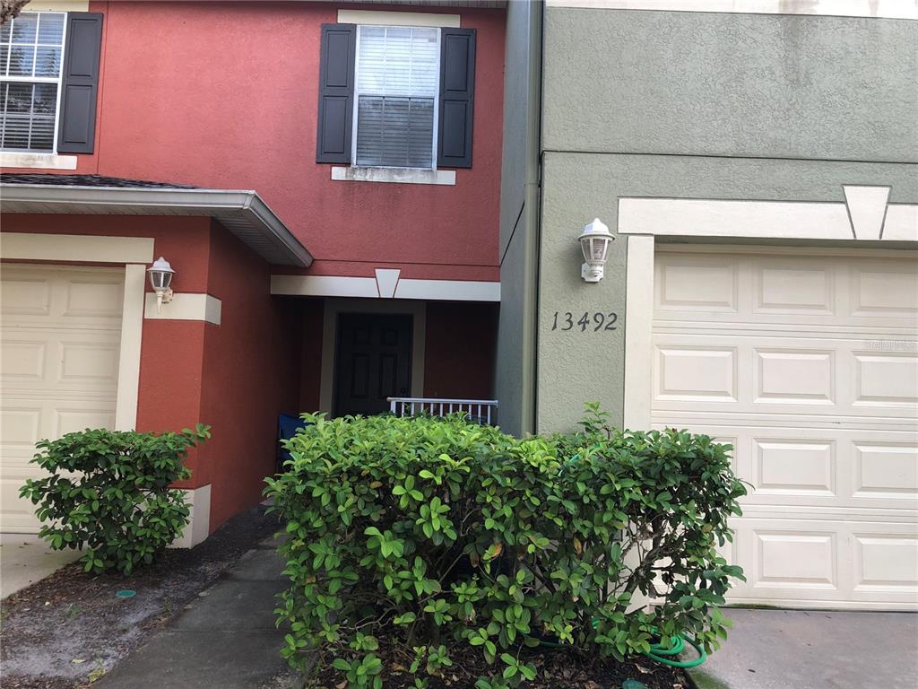 A red and green two-story townhouse exterior features two garage doors and a front entrance — 13492 APPLEROSE LANE UNIT 22, ORLANDO, FL