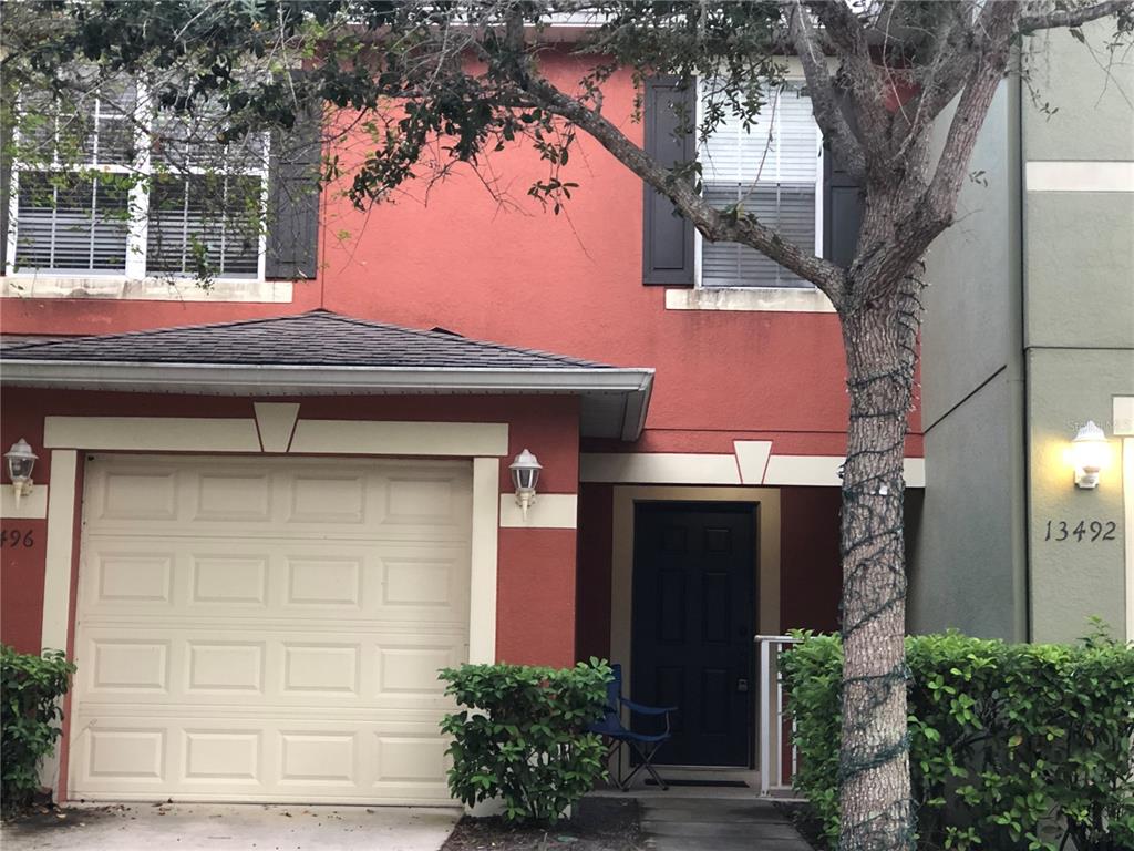 A two-story townhouse with a red stucco exterior, a single-car garage, and a front entrance — 13492 APPLEROSE LANE UNIT 22, ORLANDO, FL