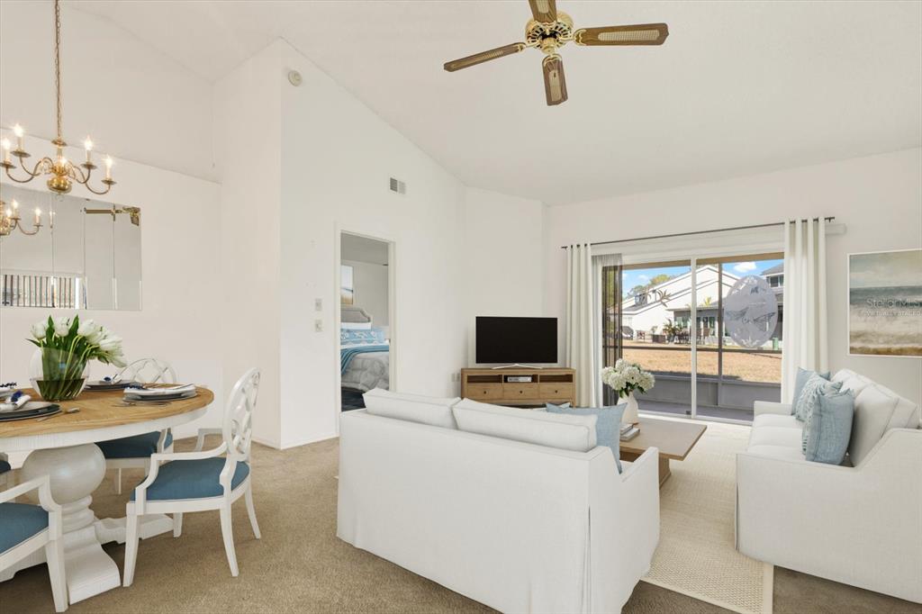 A living and dining area with white sofas, a round wooden table, and sliding glass doors — 4208 BOSTON CIRCLE, NEW PORT RICHEY, FL