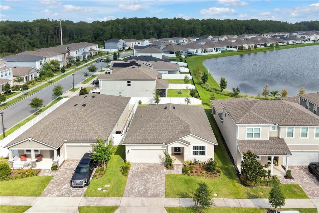 An aerial view shows suburban houses with paved driveways and a nearby lake — 8560 COMPASS POINT AVENUE, ORLANDO, FL
