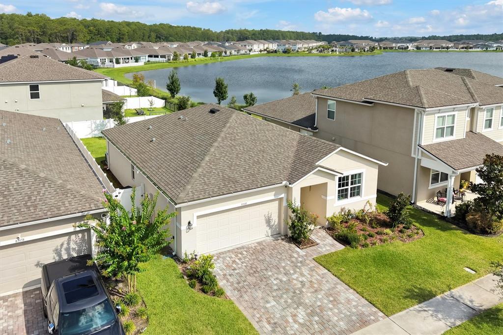 An aerial view shows a suburban house with a paved driveway and a lake behind — 8560 COMPASS POINT AVENUE, ORLANDO, FL