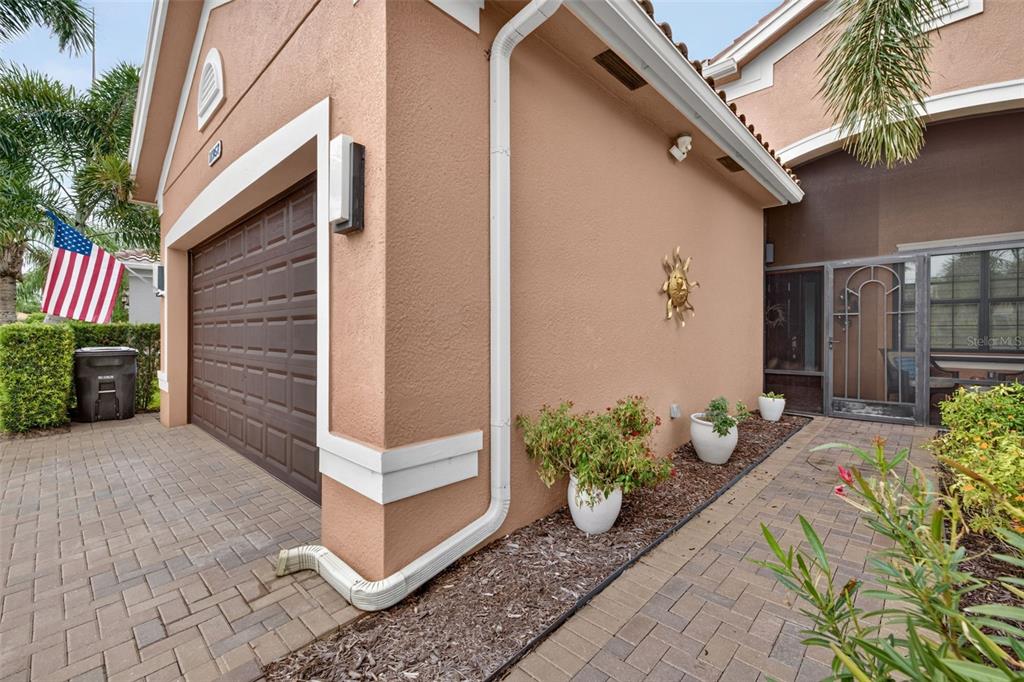 The exterior of a house features a brown garage door, a paved walkway, and potted plants — 11957 FIVE WATERS CIRCLE, FORT MYERS, FL