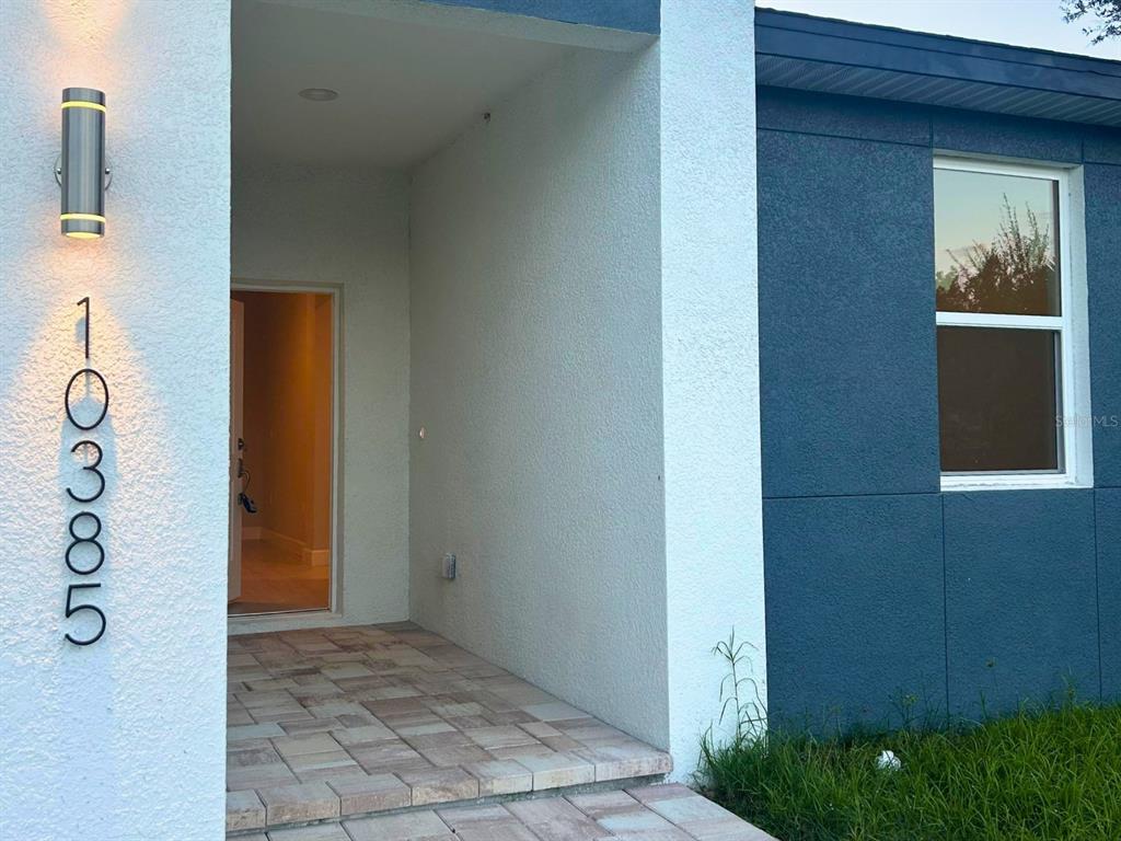 The exterior of a home features a covered entryway with a paved floor and address numbers — 10385 PORT EVERGLADES STREET, PORT CHARLOTTE, FL