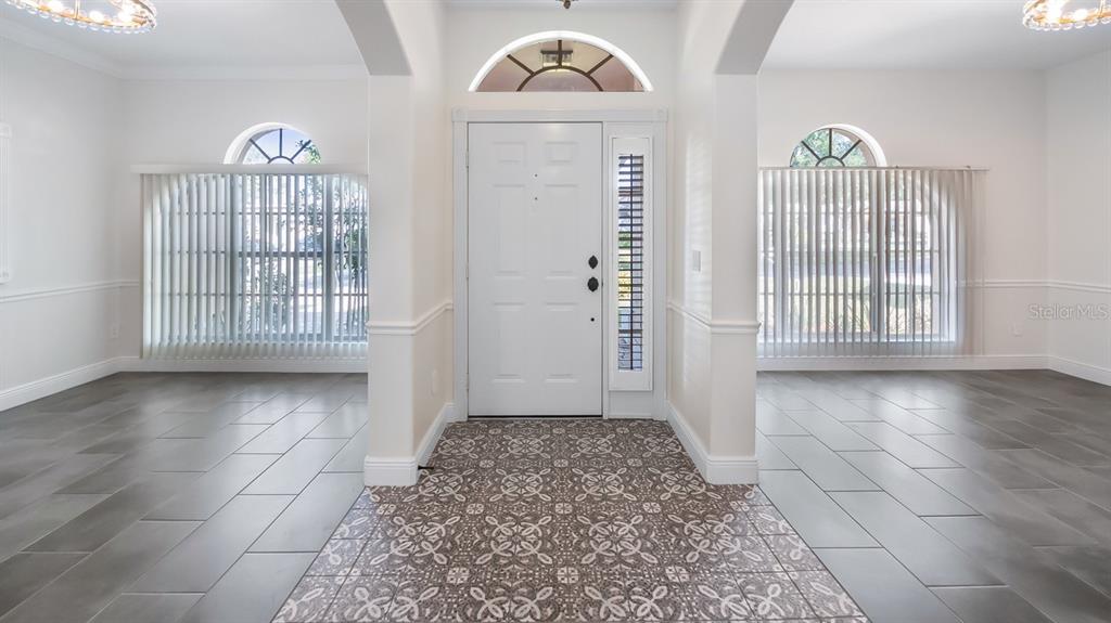 An entryway features a patterned tile floor, a white front door, and gray tile flooring — 2241 KINGSMILL WAY, CLERMONT, FL