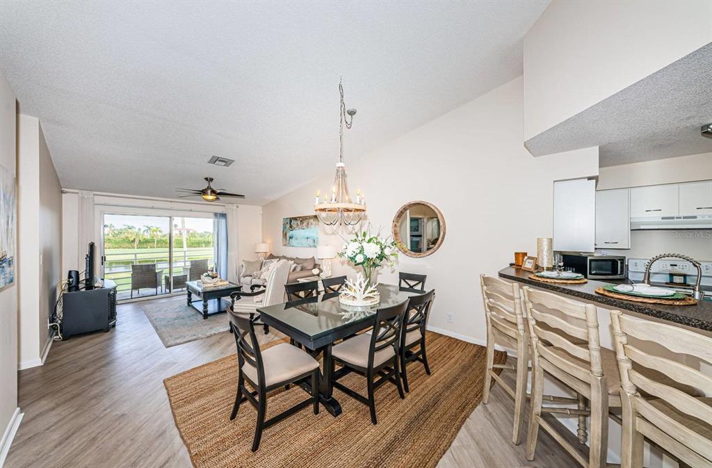 A dining area with a glass-top table and chandelier opens to a living room view — 6141 BAHIA DEL MAR BOULEVARD UNIT 229, ST PETERSBURG, FL