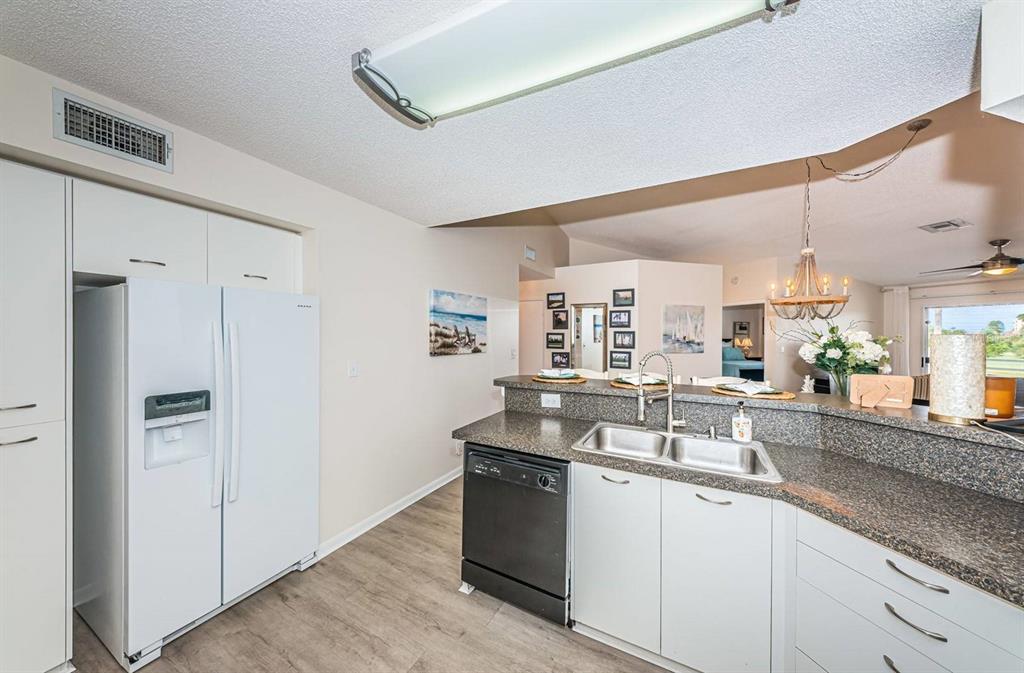 A kitchen features white cabinets, a black dishwasher, a white refrigerator, and granite countertops — 6141 BAHIA DEL MAR BOULEVARD UNIT 229, ST PETERSBURG, FL