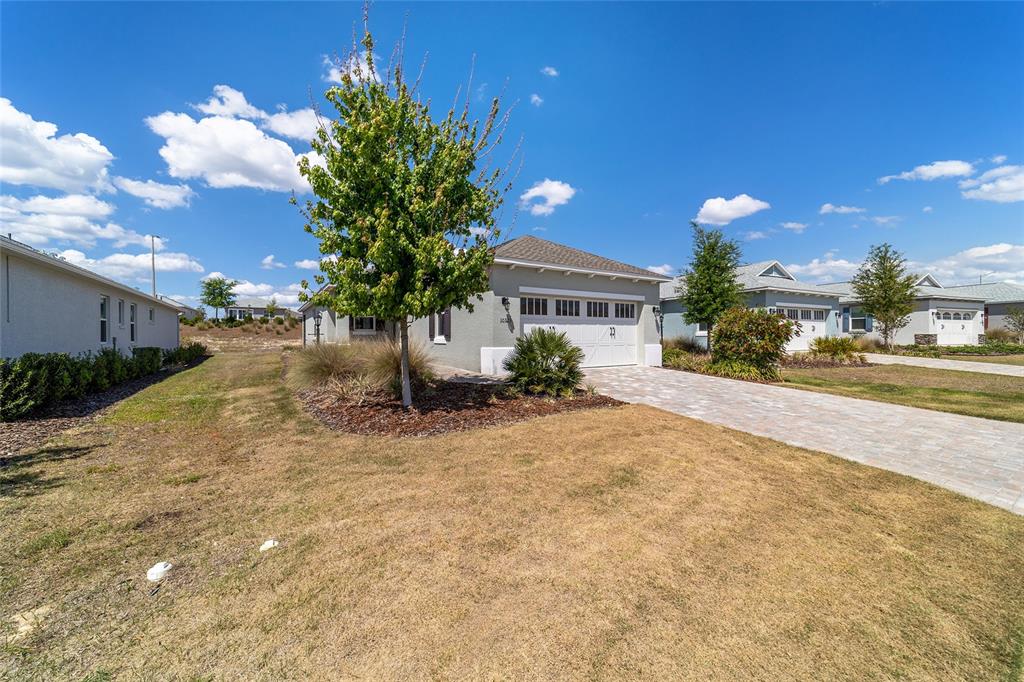 A single-story house with a paved driveway, a garage, and a tree in the front yard — 10323 SW 98TH PLACE ROAD, OCALA, FL