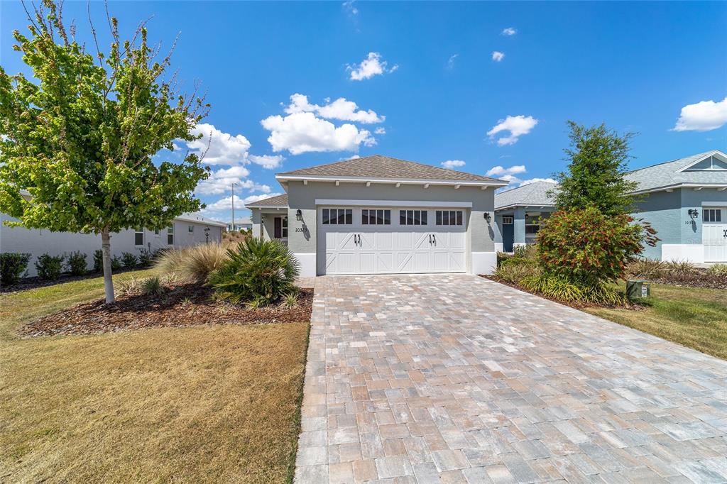 A single-story house with a white garage door and a paved driveway under a blue sky — 10323 SW 98TH PLACE ROAD, OCALA, FL