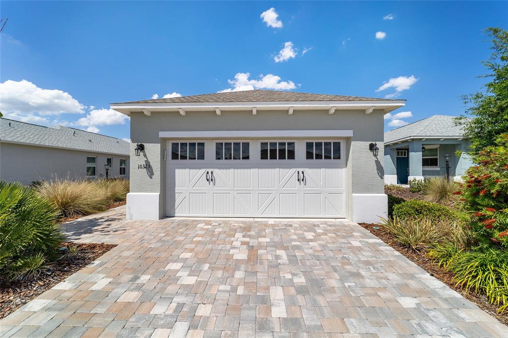 A detached two-car garage with a paver driveway and light-colored stucco exterior — 10323 SW 98TH PLACE ROAD, OCALA, FL