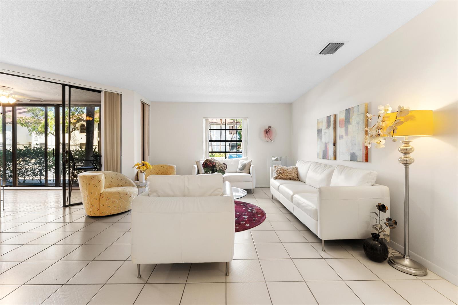 A living room features white tile floors, a white sofa, and a yellow floor lamp — 5226 Europa Drive # G, Boynton Beach FL 33437, BOYNTON BEACH, FL