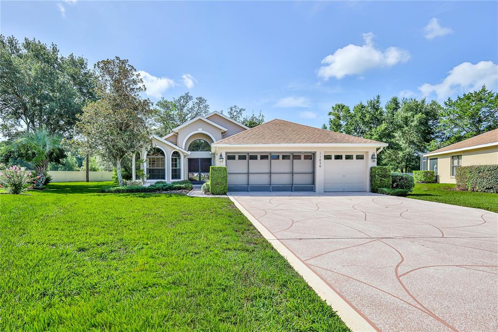 A single-story house with a beige exterior, a three-car garage, and a large front lawn — 11430 KINGSTREE COURT, SPRING HILL, FL