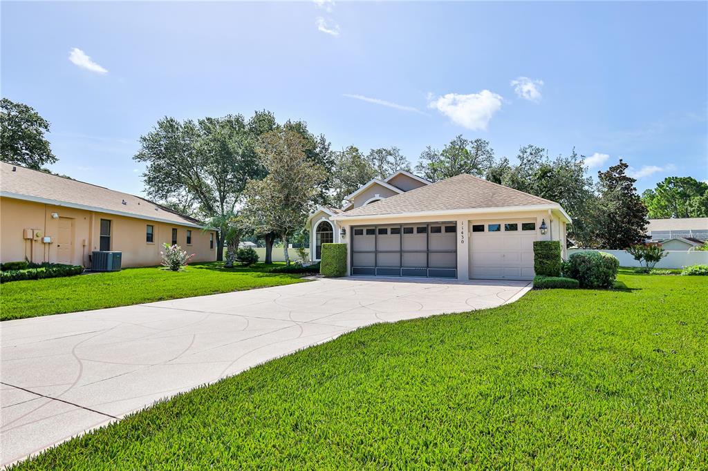 A single-story house with a beige exterior, a three-car garage, and a concrete driveway — 11430 KINGSTREE COURT, SPRING HILL, FL
