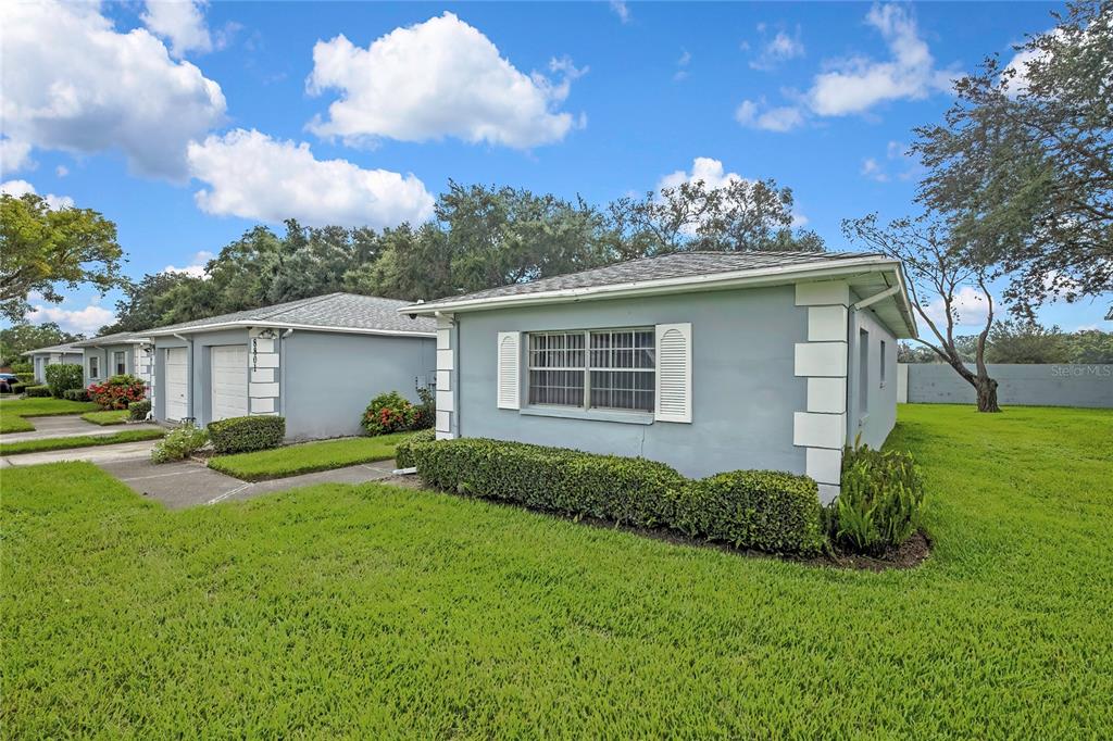 A light blue single-story house with a white-trimmed window and a green lawn — 8801 MANOS CIRCLE UNIT 8801, NEW PORT RICHEY, FL