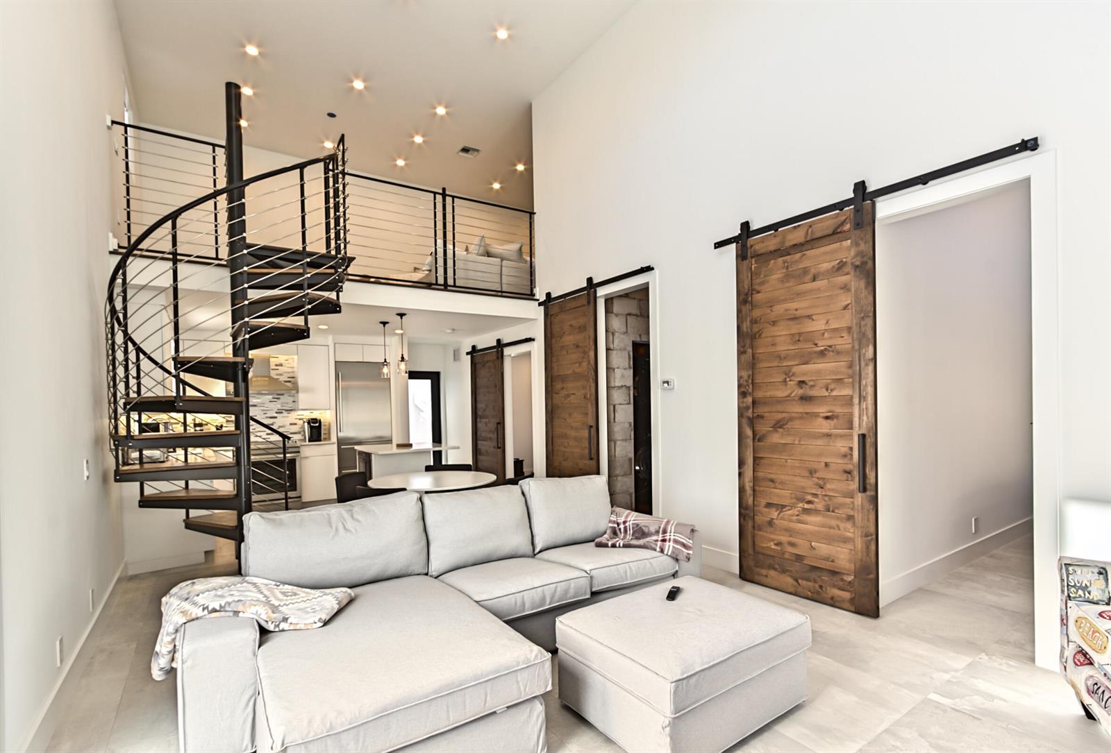 A living room features a spiral staircase, a loft area, and two wooden barn doors — 1955 NE 4th Street Unit 1, Deerfield Beach FL 33441, DEERFIELD BEACH, FL