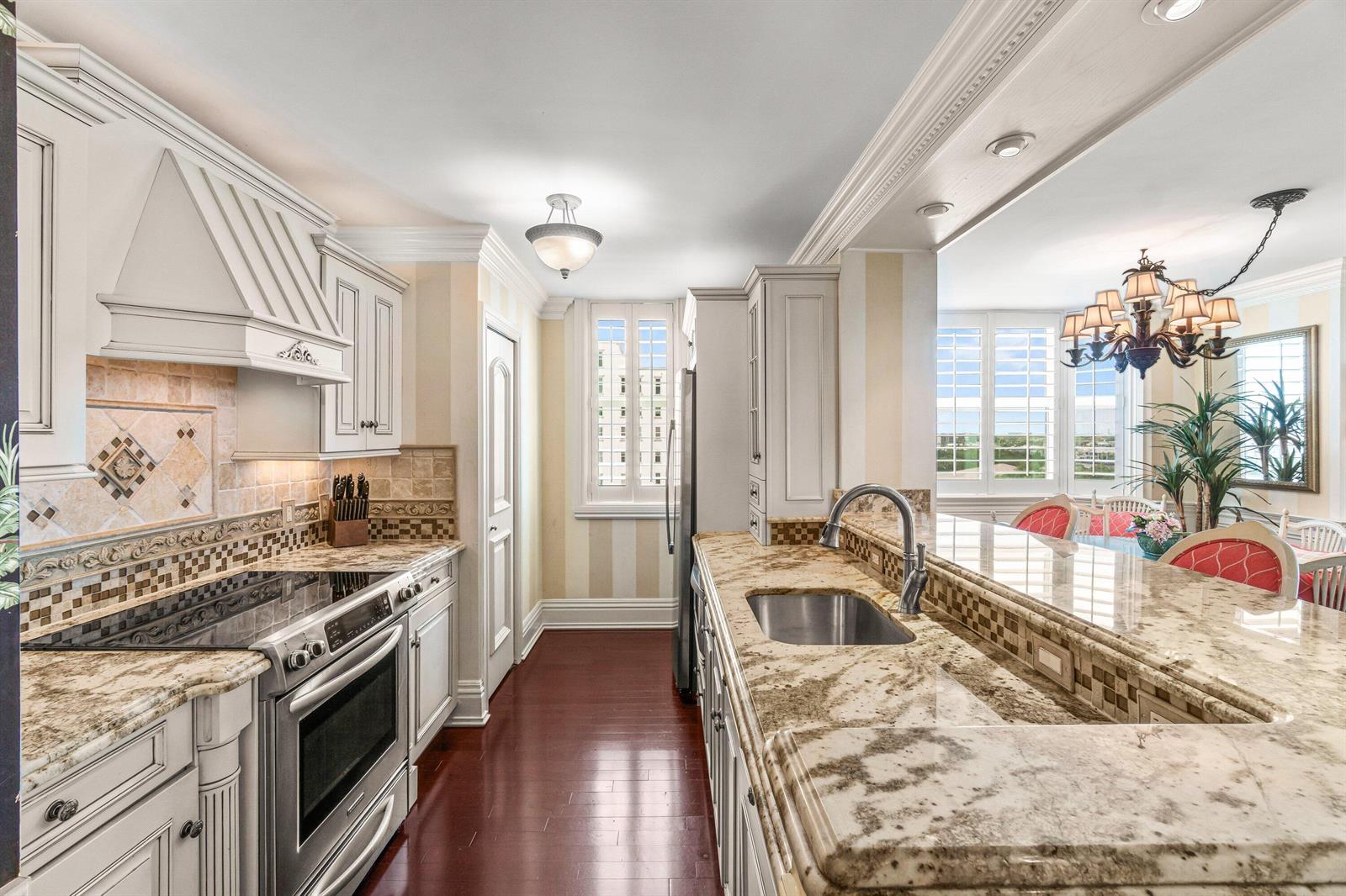 A kitchen with granite countertops, stainless steel appliances, and wood flooring opens to a dining area — 3594 S Ocean Boulevard # 801, Highland Beach FL 33487, HIGHLAND BEACH, FL