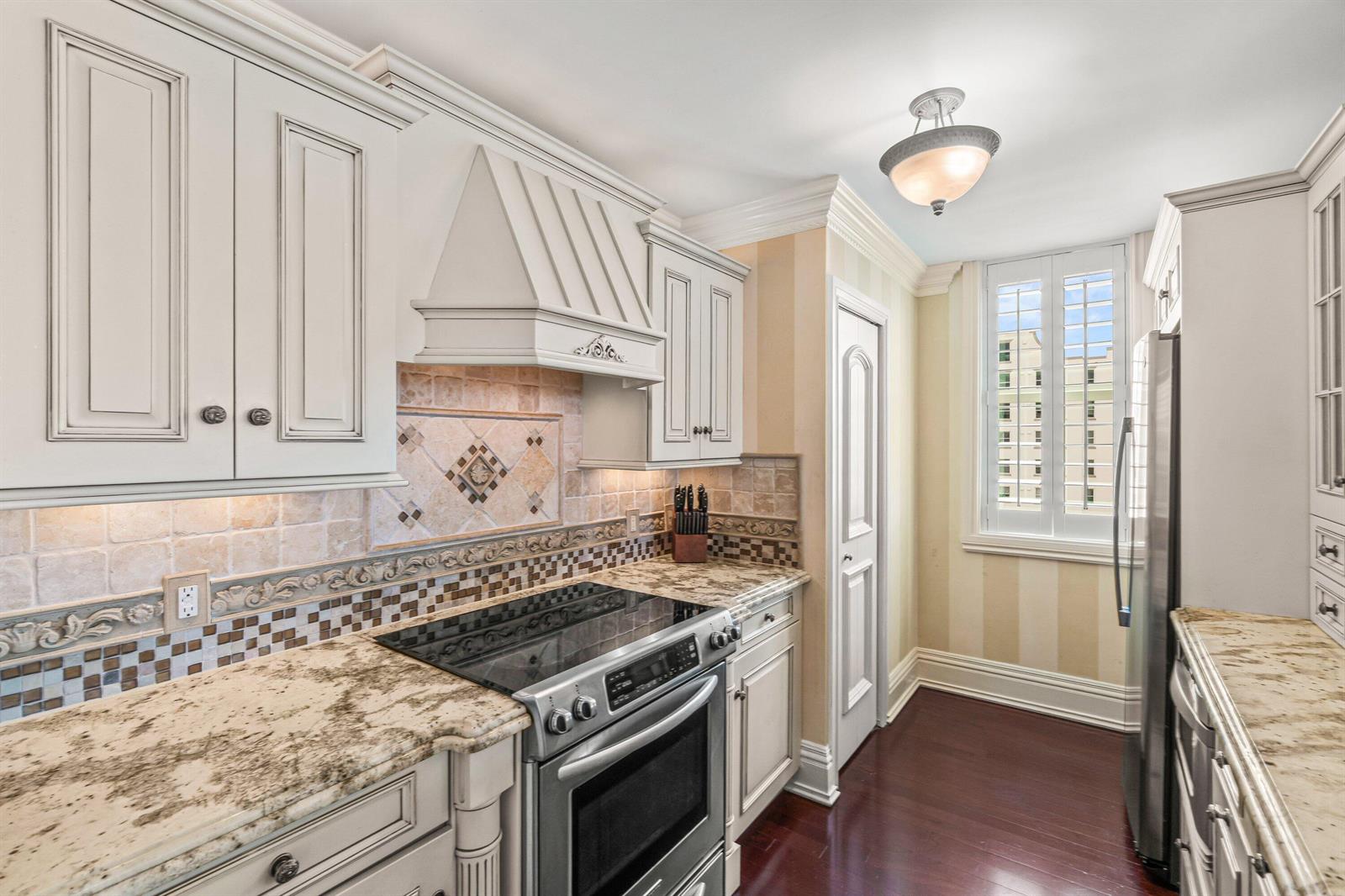 A kitchen features cream-colored cabinets, granite countertops, a tiled backsplash, and stainless steel appliances — 3594 S Ocean Boulevard # 801, Highland Beach FL 33487, HIGHLAND BEACH, FL