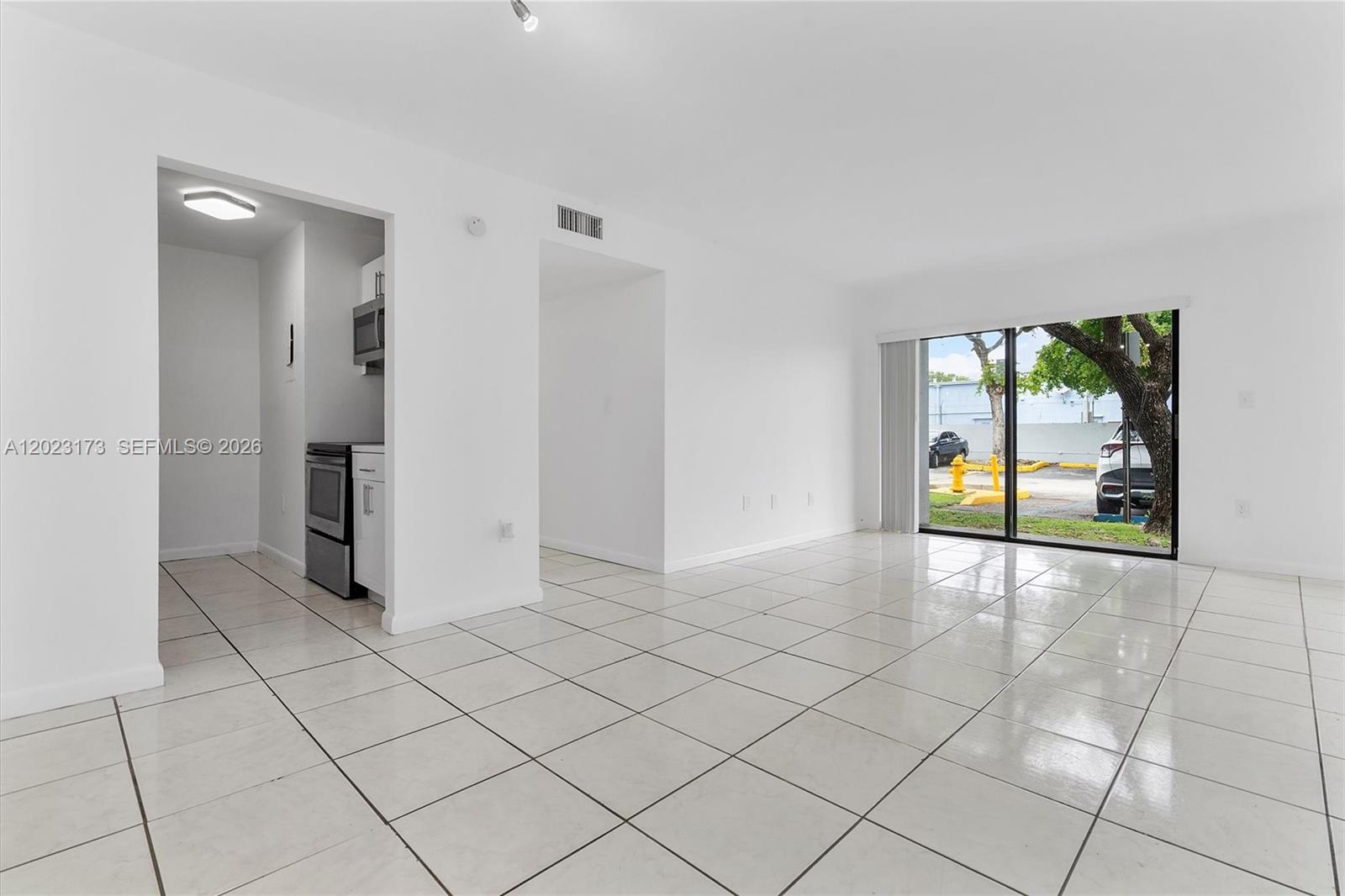 A bright, tiled living area features a kitchen pass-through and sliding glass doors to outside — 7407 SW 152nd Ave # 103, Miami FL 33193, MIAMI, FL