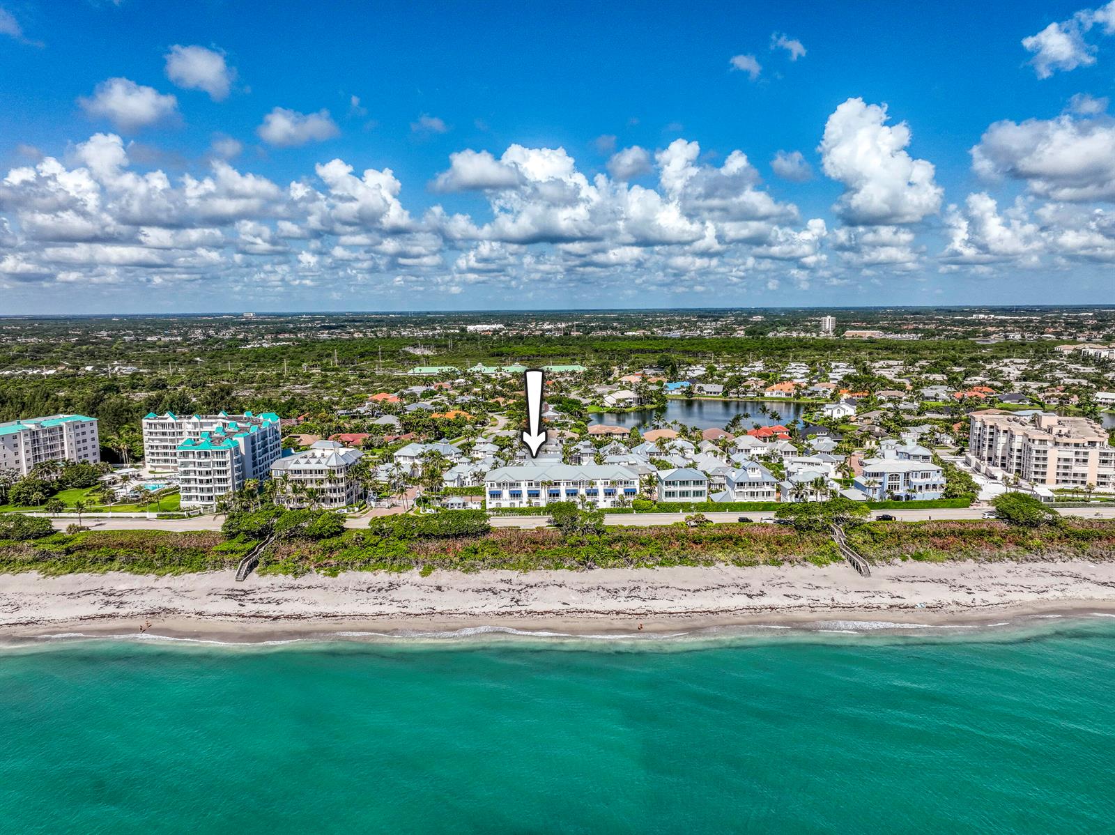 An aerial view of a beachfront residential complex with a white arrow pointing downward — 115 Ocean Key Way, Jupiter FL 33477, JUPITER, FL