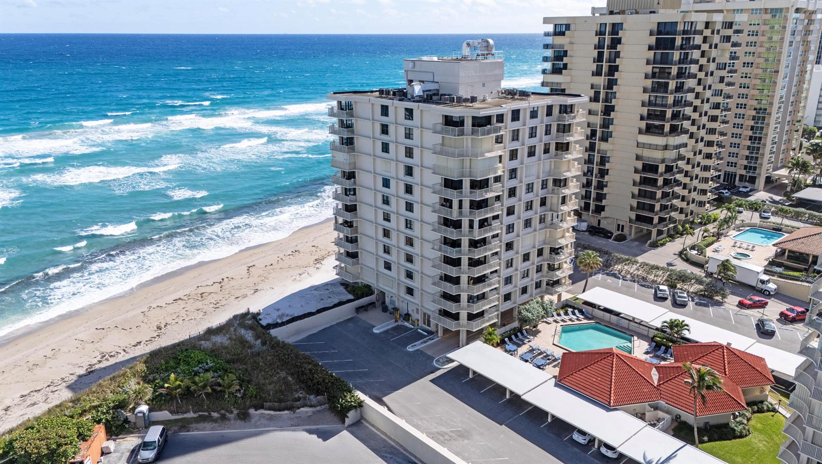 An aerial view shows a beachfront high-rise condominium building with a pool and parking lot — 5480 N Ocean Drive, Singer Island FL 33404, SINGER ISLAND, FL