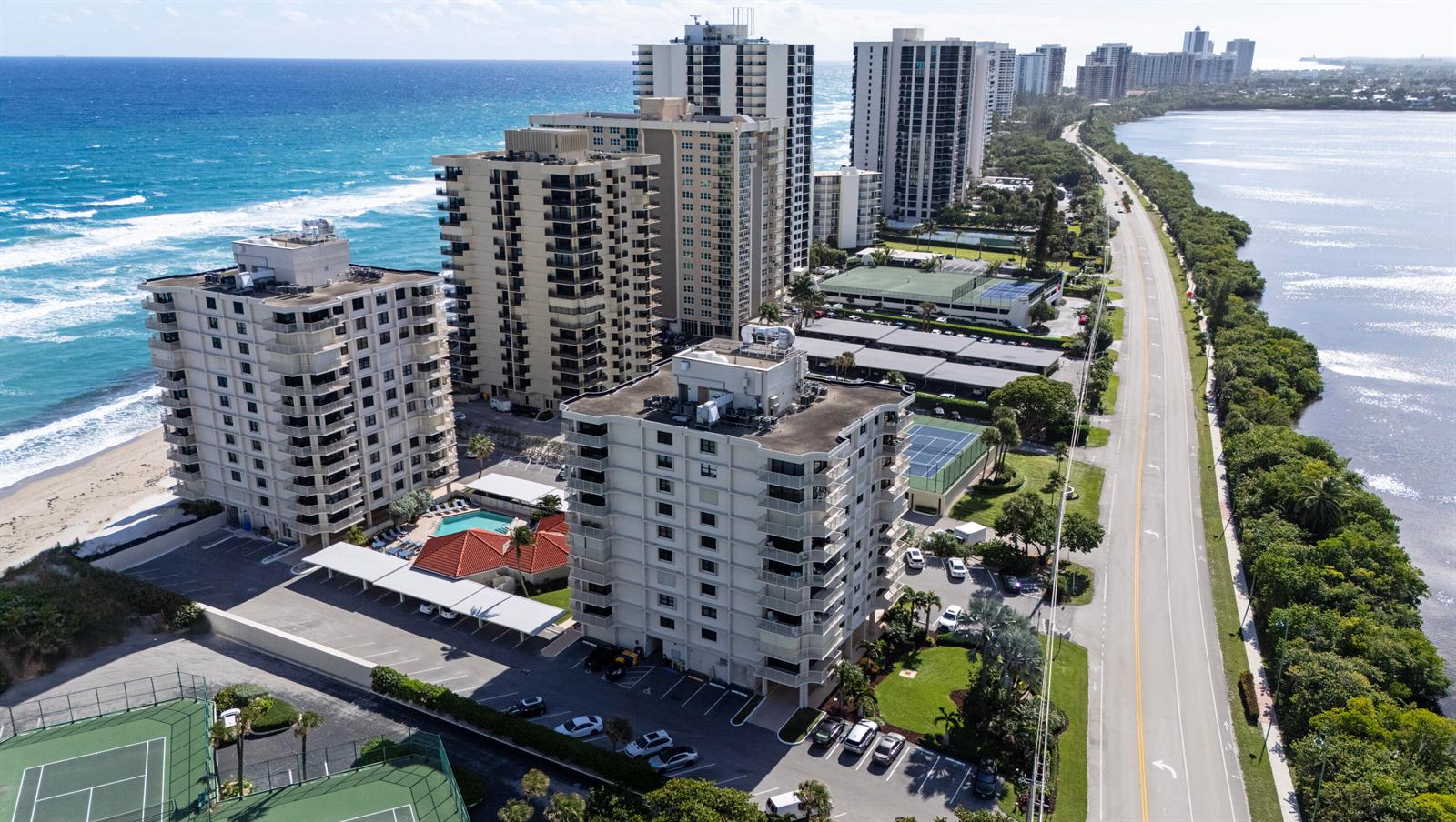 An aerial view shows high-rise apartment buildings situated between the ocean and a coastal road — 5480 N Ocean Drive, Singer Island FL 33404, SINGER ISLAND, FL