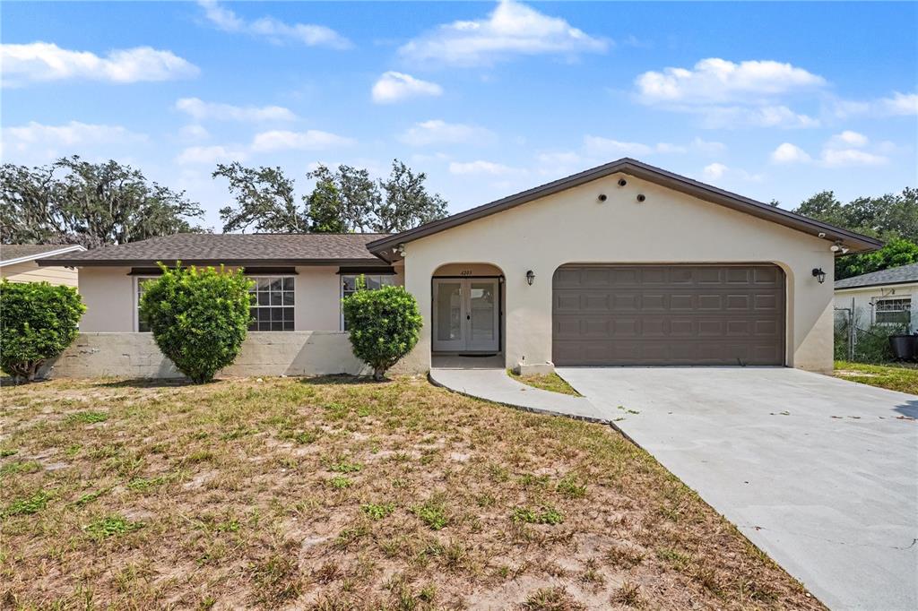 A single-story house with a beige stucco exterior, a brown garage door, and a concrete driveway — 6203 TEBBETTS DRIVE, ORLANDO, FL