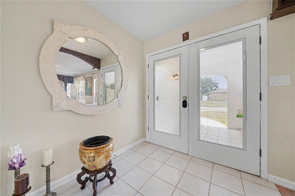 An entryway features a large decorative mirror, a ceramic planter on a stand, and double doors — 6203 TEBBETTS DRIVE, ORLANDO, FL