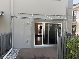 A concrete patio with a metal awning sits outside a sliding glass door — 1134 RUE DES ROIS UNIT 1134, ST PETERSBURG, FL