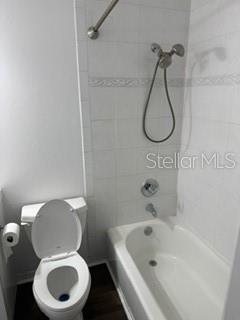 A bathroom features a white toilet next to a bathtub with a handheld shower head — 1134 RUE DES ROIS UNIT 1134, ST PETERSBURG, FL