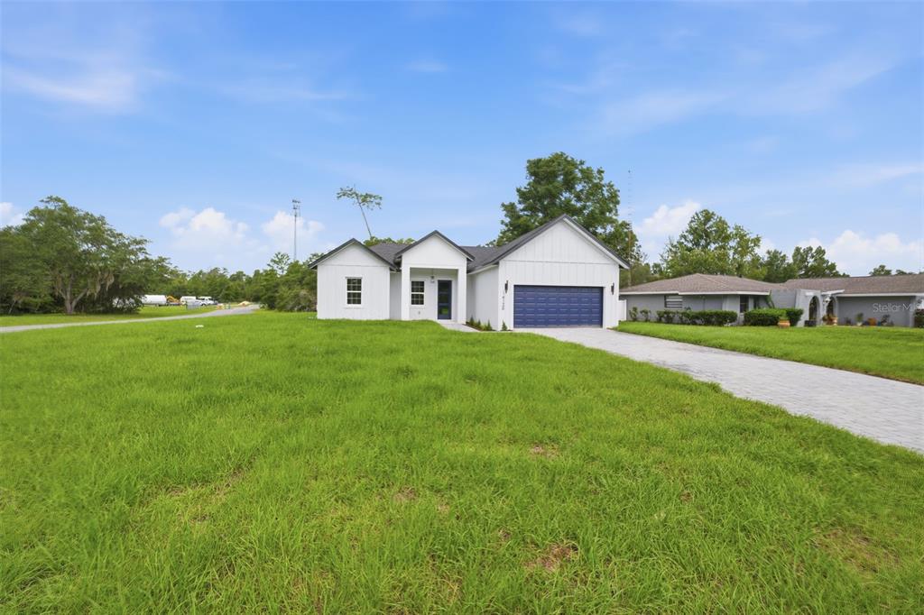 A modern white single-story house with a blue garage door sits on a grassy lot — 14126 SW 34TH TERRACE ROAD, OCALA, FL
