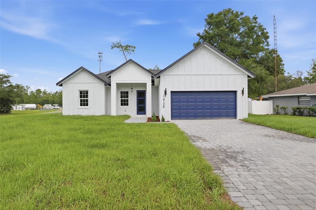 A white farmhouse-style house features a blue garage door and a paved driveway — 14126 SW 34TH TERRACE ROAD, OCALA, FL