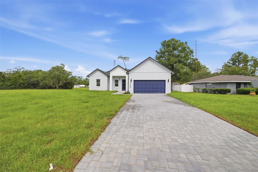 A white single-story house with a blue garage door and a paved driveway — 14126 SW 34TH TERRACE ROAD, OCALA, FL