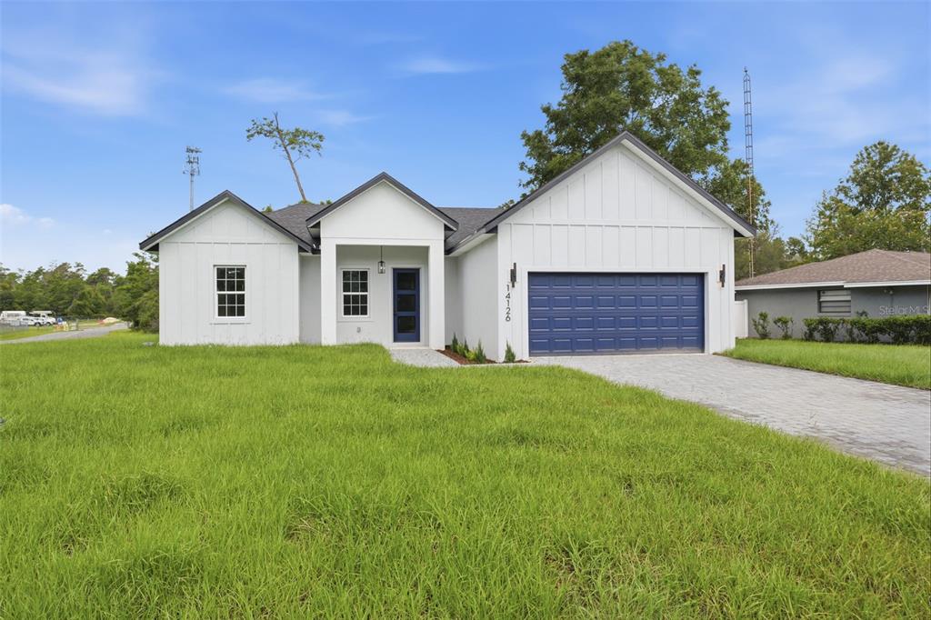 A white modern farmhouse with a blue garage door and a paved driveway — 14126 SW 34TH TERRACE ROAD, OCALA, FL