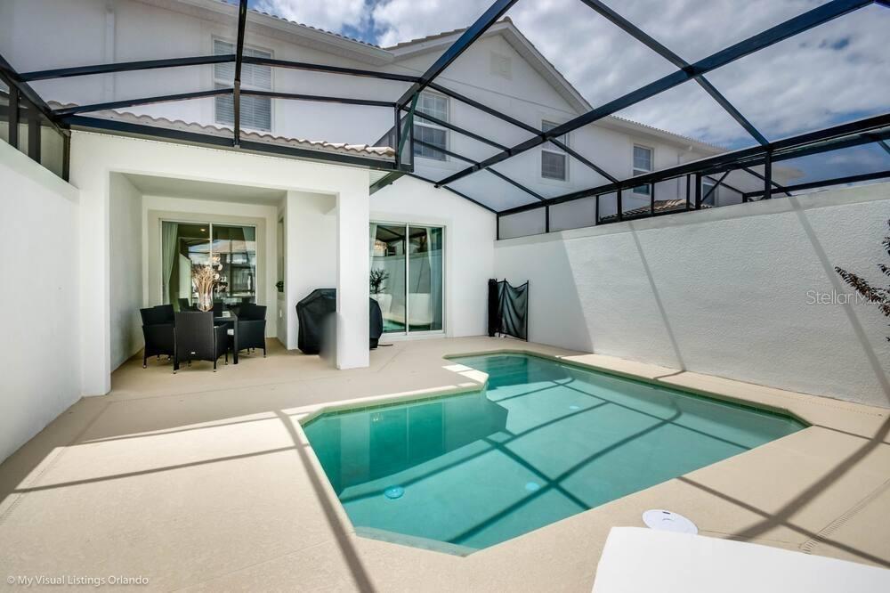 A screened-in patio features a small swimming pool and a covered outdoor dining area — 1581 SANDBAGGER DRIVE, DAVENPORT, FL
