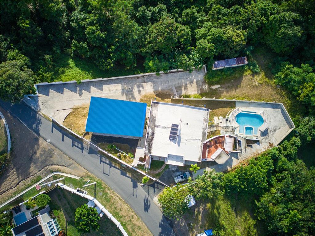 An aerial view shows a house with a blue roof, swimming pool, and surrounding trees — Carr. 115 KM 11.4 INT SECTOR JULIO SOTO, RINCON, PR