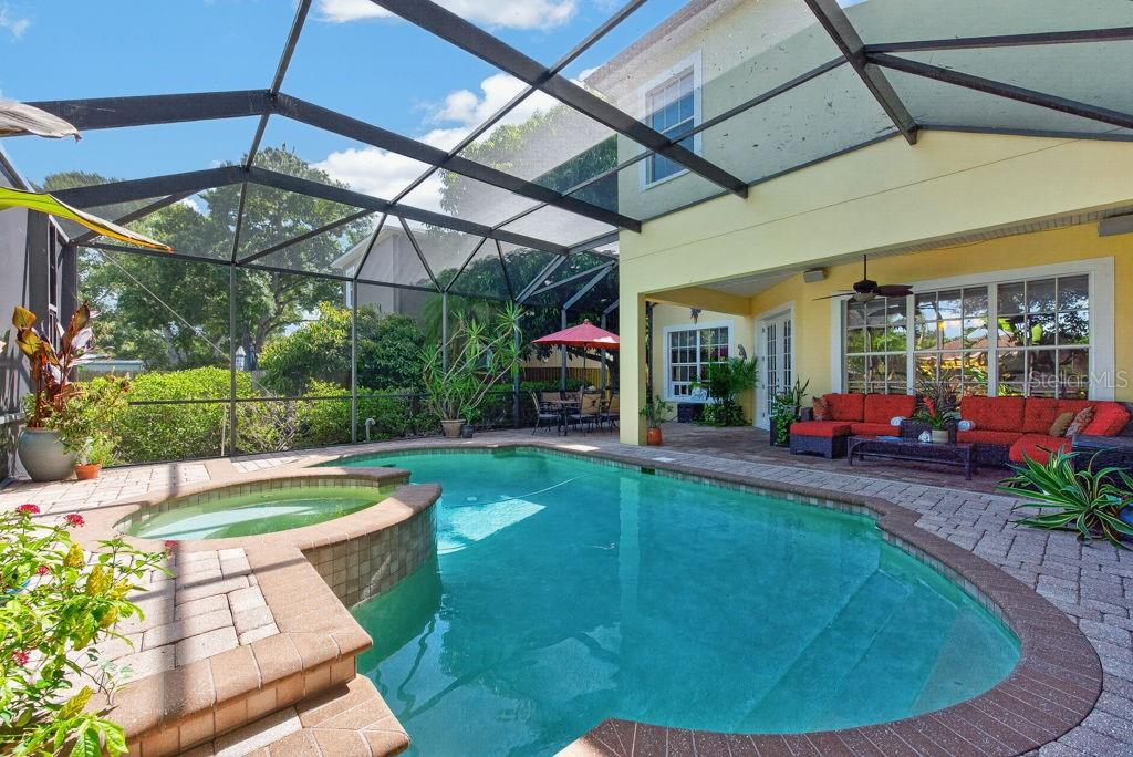 A screened-in patio features a swimming pool, a hot tub, and outdoor seating furniture — 5916 S 6TH STREET, TAMPA, FL