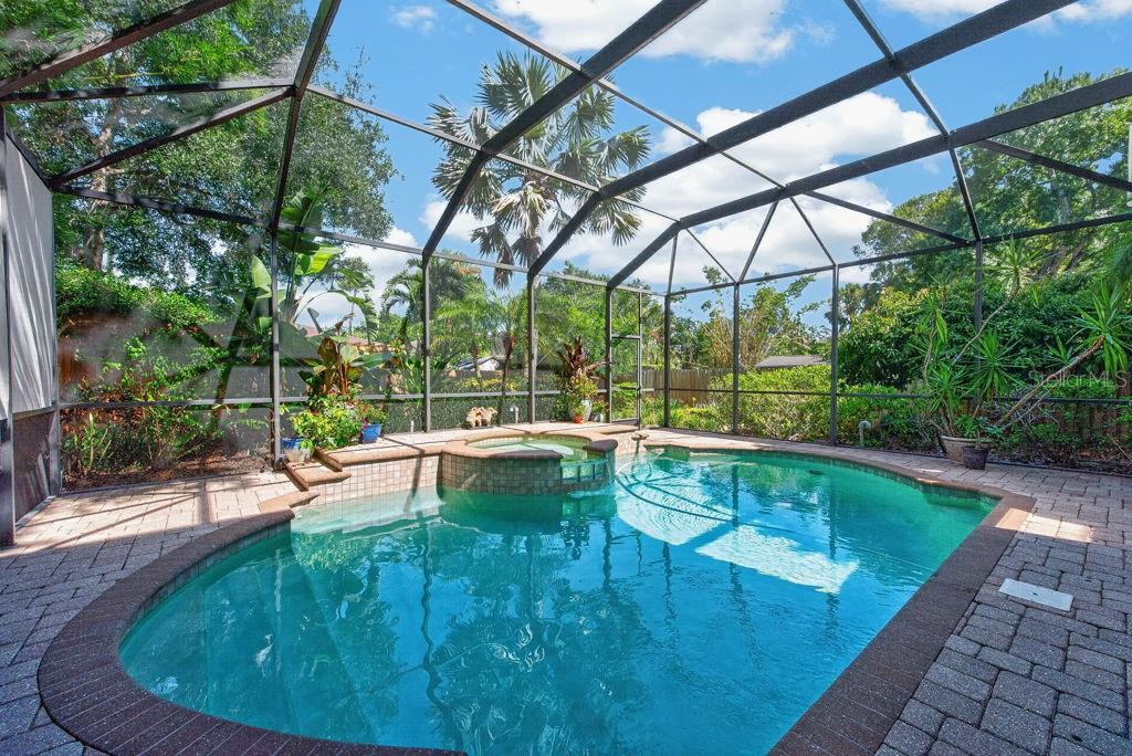 A screened-in swimming pool and hot tub with a brick paver deck and tropical landscaping — 5916 S 6TH STREET, TAMPA, FL