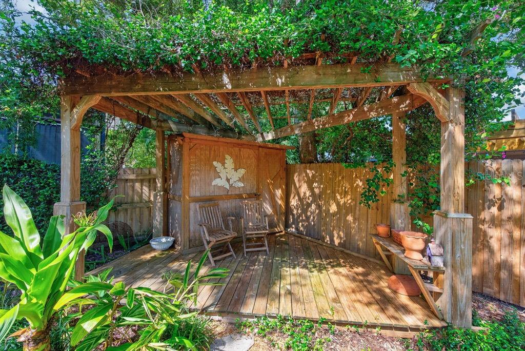 A wooden pergola covers a deck with two chairs, a storage shed, and a bench — 5916 S 6TH STREET, TAMPA, FL